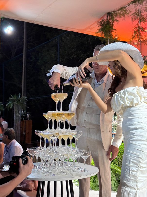 Casal despejando champanhe na torre de taças