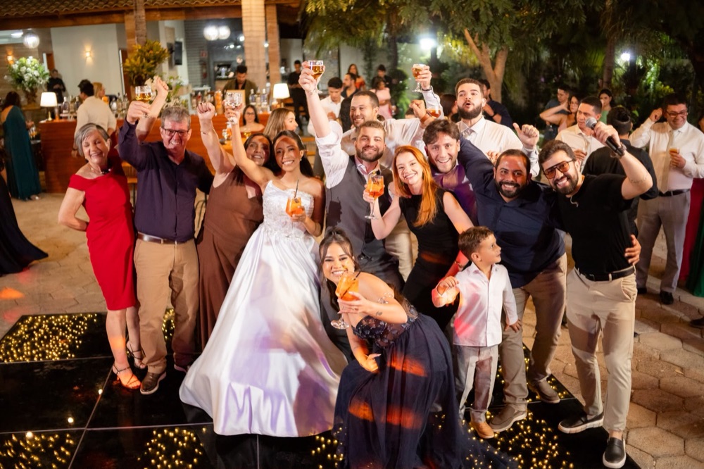 Noiva e convidados erguendo drinks na pista de dança do casamento